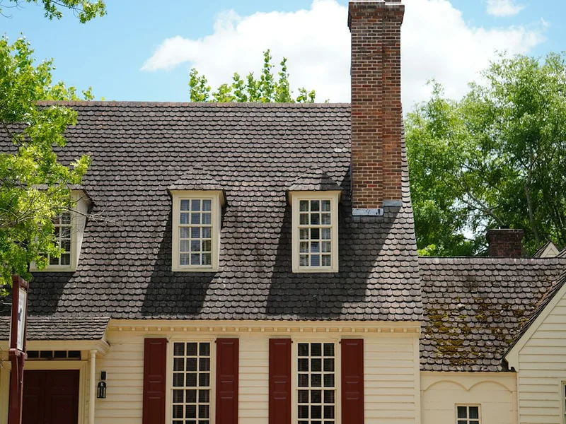 a white house with red shutters and a chimney